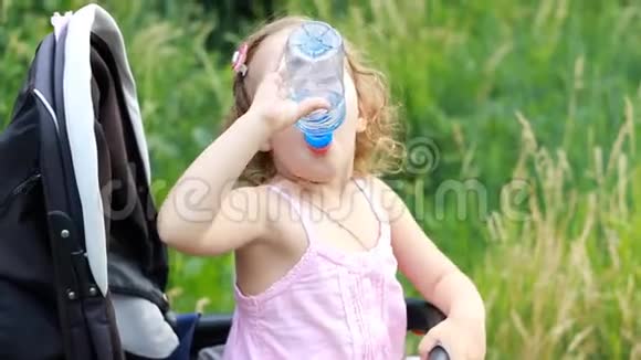 小女孩坐在婴儿车里从瓶子里喝水视频的预览图