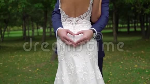 当他的双臂围绕着他的新娘时新郎在做心脏标志视频的预览图