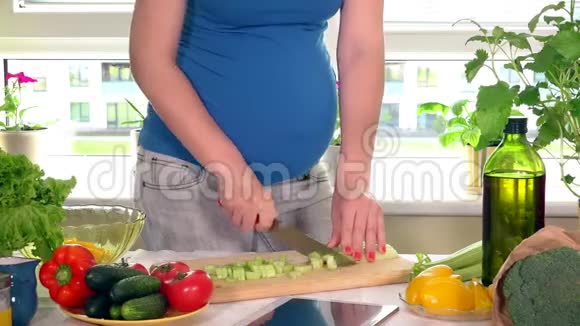 怀孕少女的胃和手用刀子切芹菜叶做沙拉视频的预览图