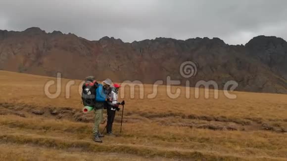 高山高原上戴着大背包戴着帽子戴着墨镜的一对旅人的鸟瞰图视频的预览图