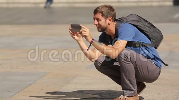 好奇的男游客用手机在城市广场拍照视频的预览图