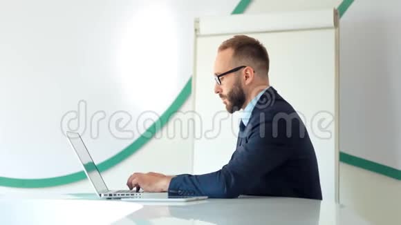 西装革履戴着眼镜穿着白色办公室笔记本电脑的漂亮商人视频的预览图