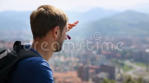 男性游客俯瞰大城市用手遮挡太阳旅游视频的预览图
