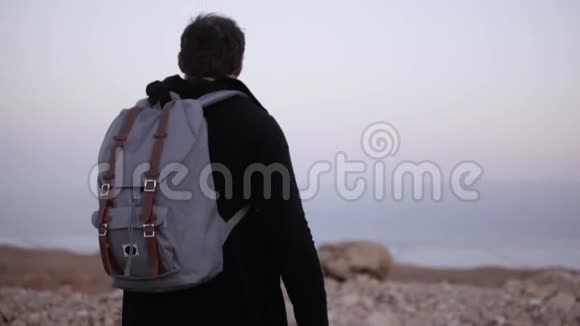 带背包的人在沙漠里散步慢动作年轻的雄性独自在黄昏的荒野中游荡风景优美的山天以色列视频的预览图