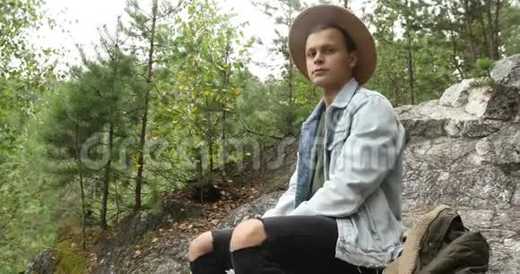 坐在森林悬崖上的年轻人视频的预览图