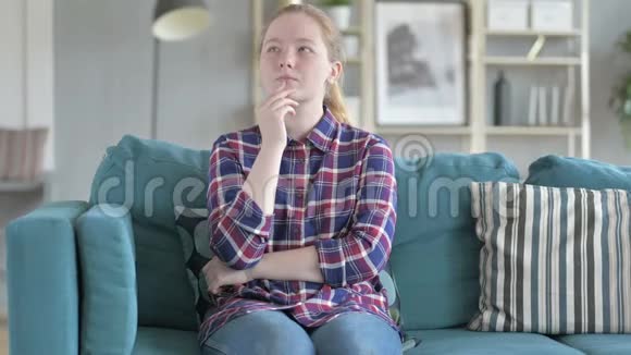 坐在沙发上思考的年轻女人视频的预览图
