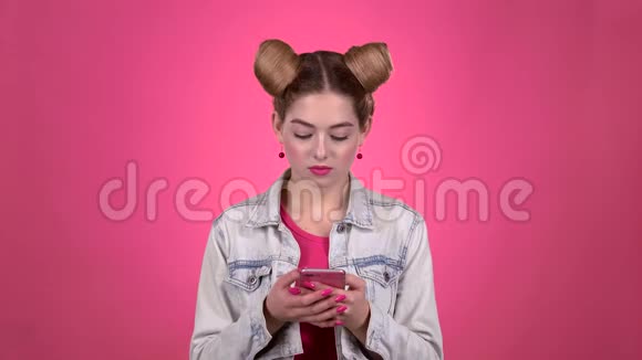 女孩正在测试一部手机竖起大拇指粉色背景慢动作视频的预览图