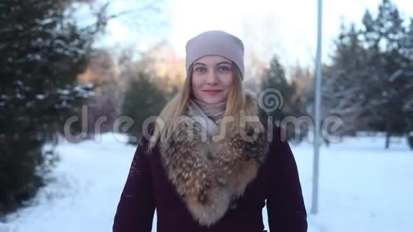 一个漂亮的女孩点头哈腰地穿过冬天的公园视频的预览图