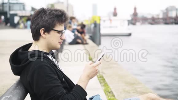 穿短裤的年轻人在德国奥伯鲍姆桥附近发短信和微笑视频的预览图