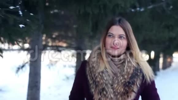 一个美丽时尚的女孩带着好心情走过冬天的公园笑容甜美视频的预览图
