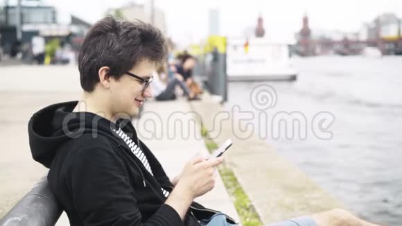 穿短裤的年轻人在德国奥伯鲍姆桥附近发短信和微笑视频的预览图