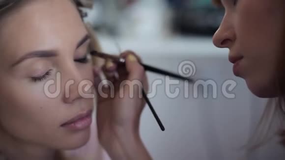 特写镜头化妆师是根据美容院里女孩的条款化妆的视频的预览图