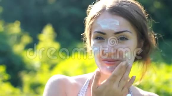 一位年轻的女士正在从阳光下涂上防晒霜视频的预览图