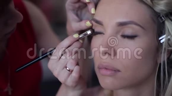 特写镜头化妆师造型师在美容院为一个女孩塑造形象视频的预览图