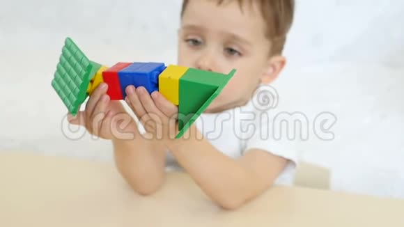 一个孩子正在玩彩色积木慢动作地坐在白色背景上的桌子旁孩子正拿着视频的预览图