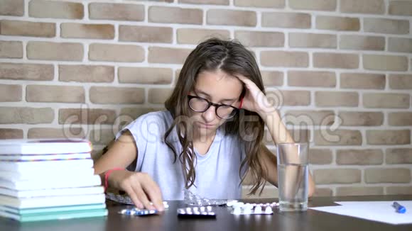 保健概念训练负荷期间的免疫一个十几岁的女孩正坐在一张桌子上端着课本和视频的预览图