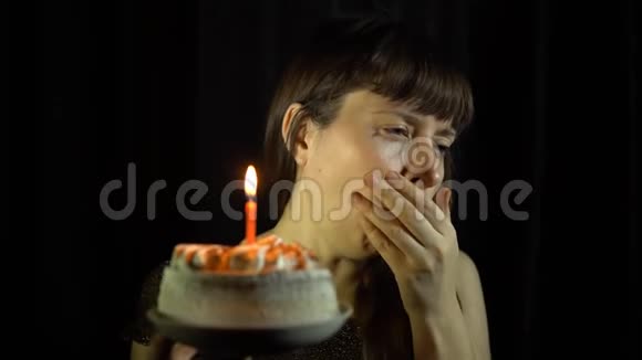 一个女人咳嗽然后在黑色背景上的蛋糕上吹灭蜡烛视频的预览图