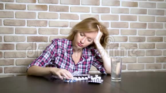 生病的悲伤的女人坐在桌边整理药片保健和维生素缺乏的概念视频的预览图
