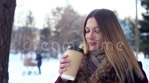肖像美丽的女孩在公园里喝咖啡冬天心情愉快视频的预览图