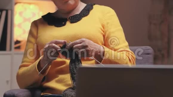 老年妇女的手在笔记本电脑附近编织视频的预览图