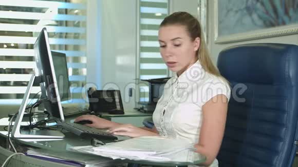一个疲惫而困倦的年轻商务女性拿着笔记本电脑坐在办公桌前视频的预览图