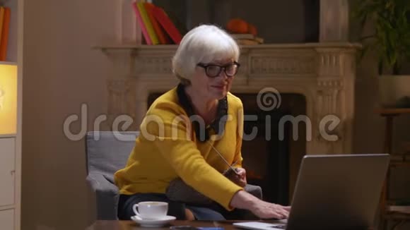 退休祖母在舒适的客厅里和孙子孙女打视频电话视频的预览图