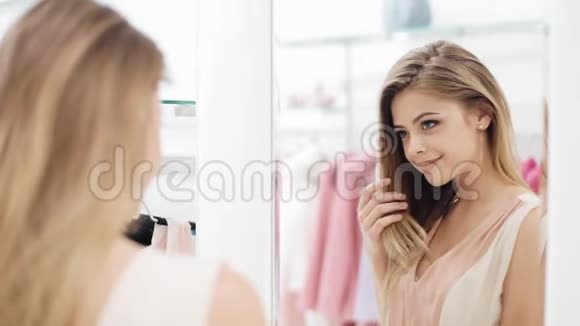 漂亮的购物女人在房间里试着靠近镜子的衣服一个年轻漂亮的女孩在购物中心的更衣室里视频的预览图