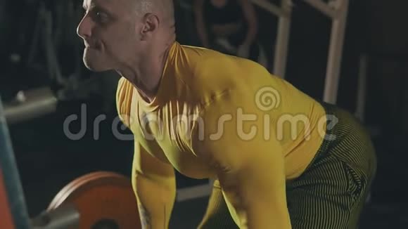穿黄色运动服的肌肉男在黑暗健身房做交叉训练视频的预览图
