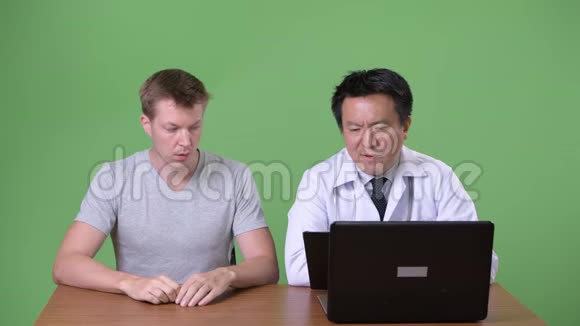 成熟的日本男性医生和年轻病人讨论视频的预览图