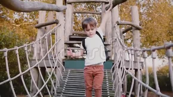 可爱的男孩在冒险公园绳索课程体贴的男孩子走在绳桥上障碍游乐场慢动作视频的预览图