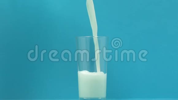 新鲜牛奶倒入蓝色背景玻璃钙和磷的来源视频的预览图