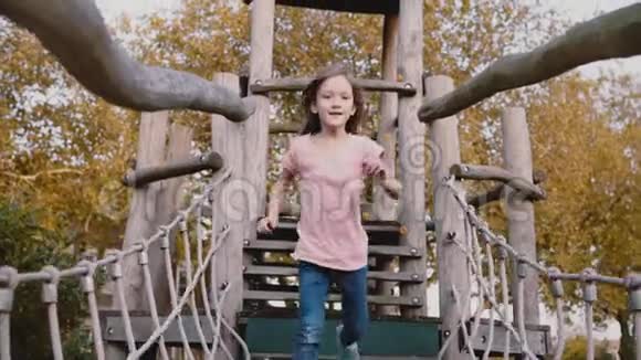 可爱的女孩在冒险公园的绳索课程快乐的孩子在有障碍的绳桥上奔跑游乐场慢动作视频的预览图