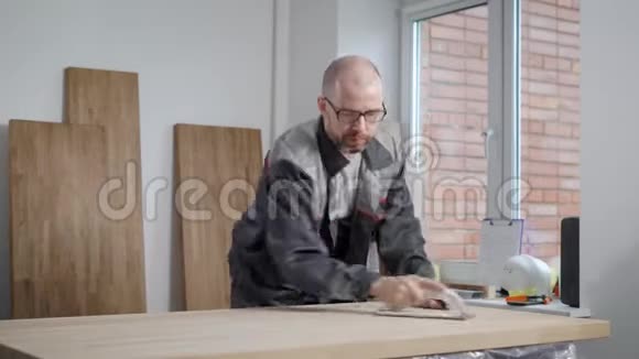 成年秃顶工人男子在木工车间用手打磨木板视频的预览图