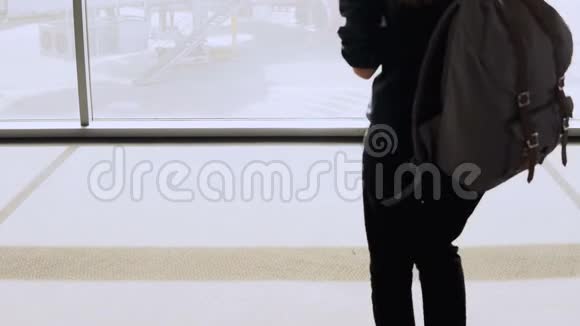 带背包的女孩走到机场休息室的窗户有智能手机的女乘客在候机楼等候女商人4K视频的预览图