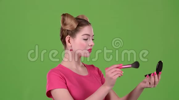 女孩手里拿着刷子把脸粉化了绿色屏幕快关门慢动作视频的预览图