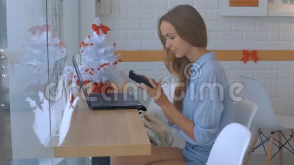 金发女孩在咖啡厅的木桌上做笔记本电脑视频的预览图