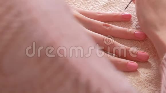 女人用小流苏把第二层粉红色的紫胶涂在她的指甲上特写双手视频的预览图