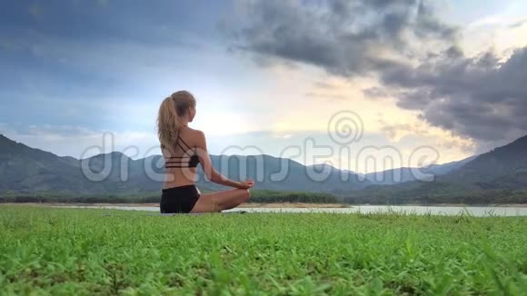 特写女孩在瑜伽姿势中思考莲花对抗丘陵地视频的预览图
