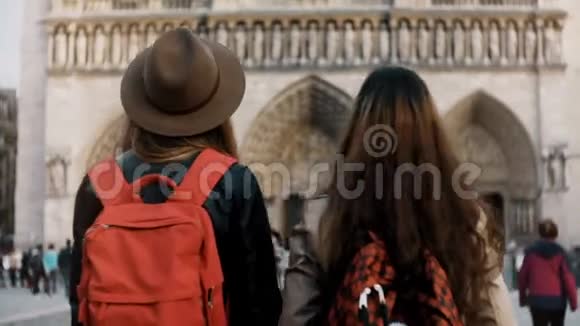 法国巴黎著名的大教堂或教堂附近两个带着红色背包散步的快乐女性视频的预览图