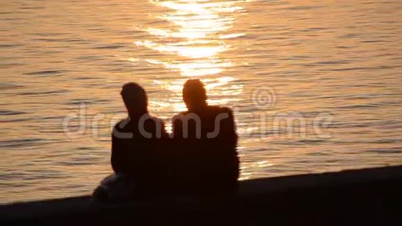 浪漫情侣在海上日落时相爱的剪影男孩和女孩享受日落和自拍与电话度假视频的预览图