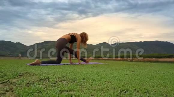 底景女性在绿色草地上保持瑜伽姿势视频的预览图