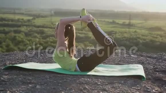 这个运动女孩在户外做瑜伽练习侧视苗条的金发女孩站在瑜伽姿势上视频的预览图