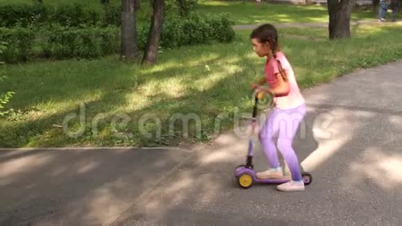 夏天小孩子在公园里骑滑板车可爱的女孩在户外玩耍儿童休闲和户外运动视频的预览图