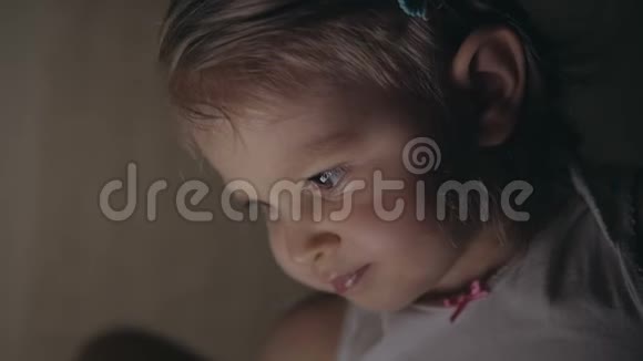一个晚上躺在床上的小女孩在电子平板电脑屏幕上点击她的手指视频的预览图