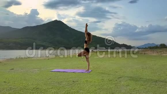绿草湖岸上的瑜伽姿势Flycam秀女孩视频的预览图