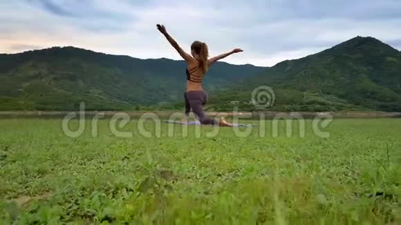 侧视女孩在湖岸瑜伽姿势中举手视频的预览图