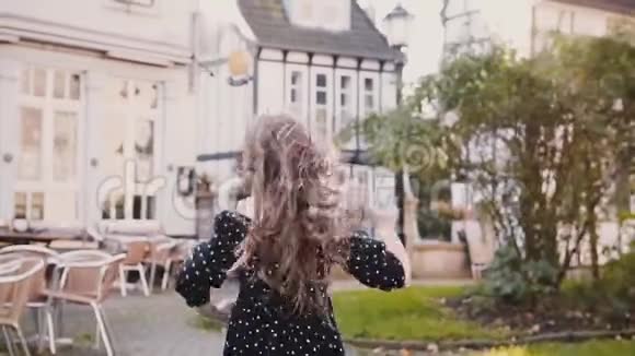 小女孩跑在美丽的神秘古镇后视慢动作铺路半木屋和墓地视频的预览图