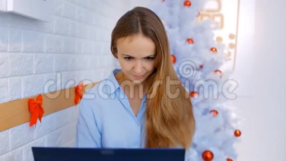 金发女郎在圣诞树附近的电脑上工作视频的预览图