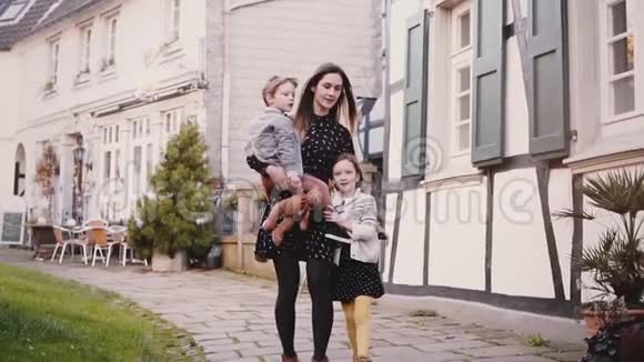 漂亮的女人和两个孩子一起走慢动作欧洲家庭妈妈男孩和女孩牵手团结一致视频的预览图