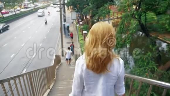金发迷人的年轻女子走在市中心穿过大桥视频的预览图